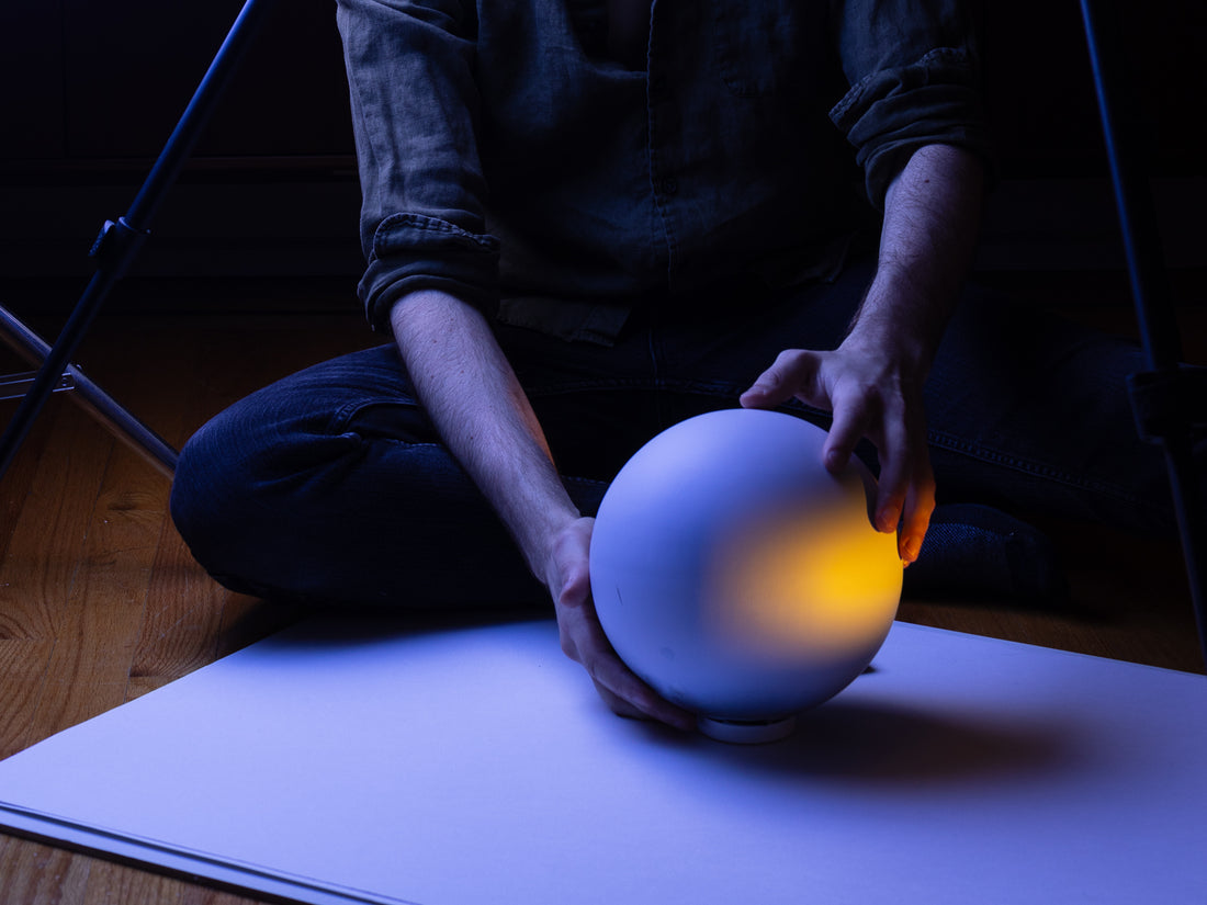 A view of the spherical sculpture with artist placing it in the light 