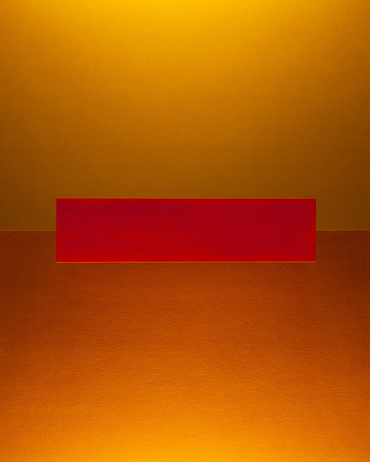 An abstract photograph of a yellow and a gold color field divided by a red rectangle of color